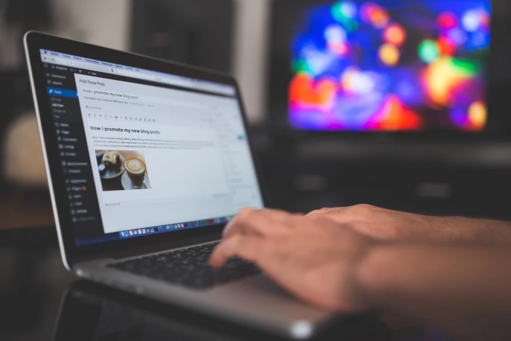 Ręce piszące na klawiaturze laptopa na której wyświetlony jest panel Wordpress